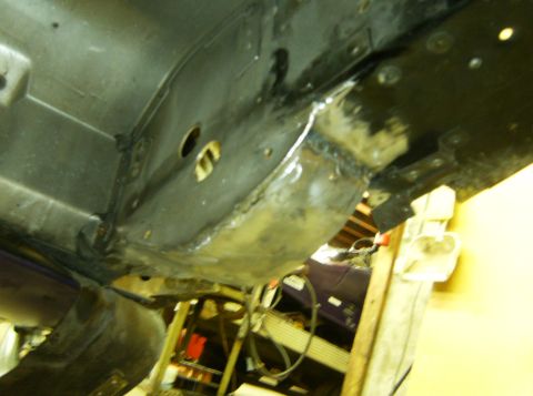 2000 Ford E350 - The underside of a vehicle frame shows fresh welds on a metal component, likely a repair or modification. Several circular holes are visibl…