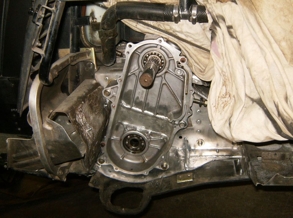 Close-up of vehicle transmission housing and engine components with a dirty cloth.