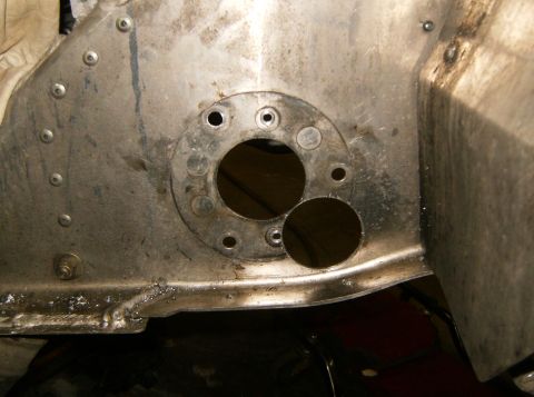 2000 Ford E350 - A close-up view of a metal panel with two circular cutouts and several bolt holes, likely part of a vehicle's chassis or engine bay.