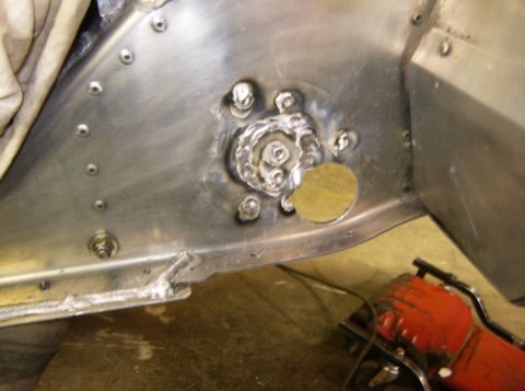 2000 Ford E350 - A close-up view shows a metal panel with several rivets and a circular patch. Welds are visible around a central circular feature with bolt…