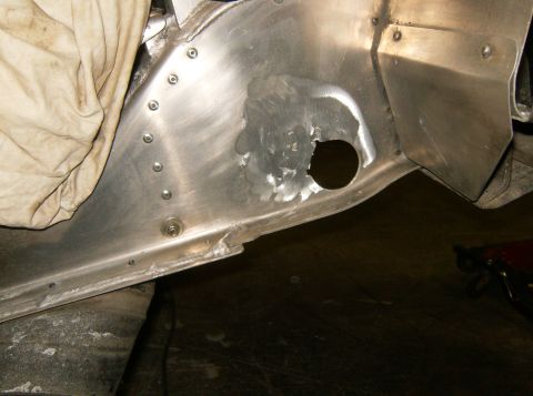 2000 Ford E350 - A close-up view of a section of a vehicle's aluminum body panel that has been repaired with a patch and rivets. A circular hole is visible…