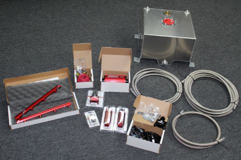 2003 Ford Crown Victoria - A collection of new automotive fuel system parts, including fuel rails, a fuel pump, and braided lines, are displayed on a carpeted surface.