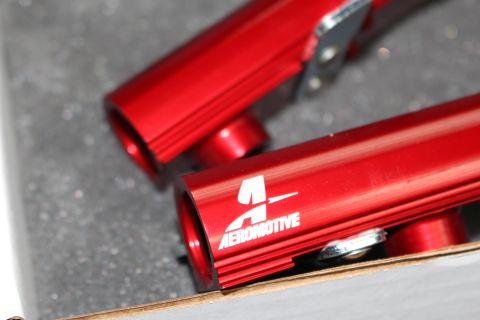 2003 Ford Crown Victoria - Close-up of red Aeromotive fuel rails, likely for an automotive application.
