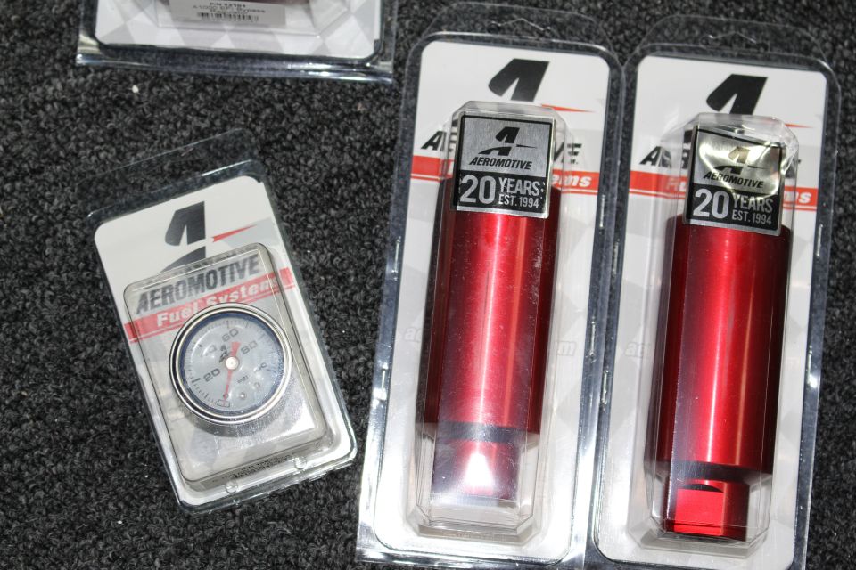 Aeromotive Fuel Systems blister packs: a pressure gauge and two red anodized parts with 20 Years labels