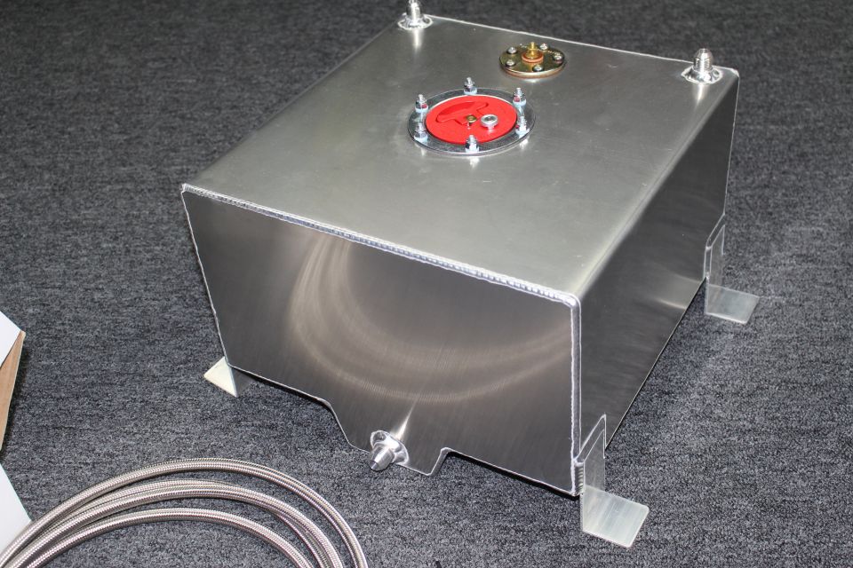 Brushed aluminum fuel cell tank with red and brass cap fittings and mounting tabs, braided line coiled nearby
