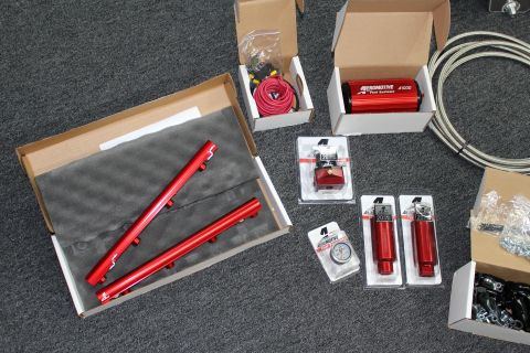 2003 Ford Crown Victoria - fuel system kit on gray carpet with red rails in a foam box, an A1000 pump, regulator, gauge, blister-packed fittings, and braided line.