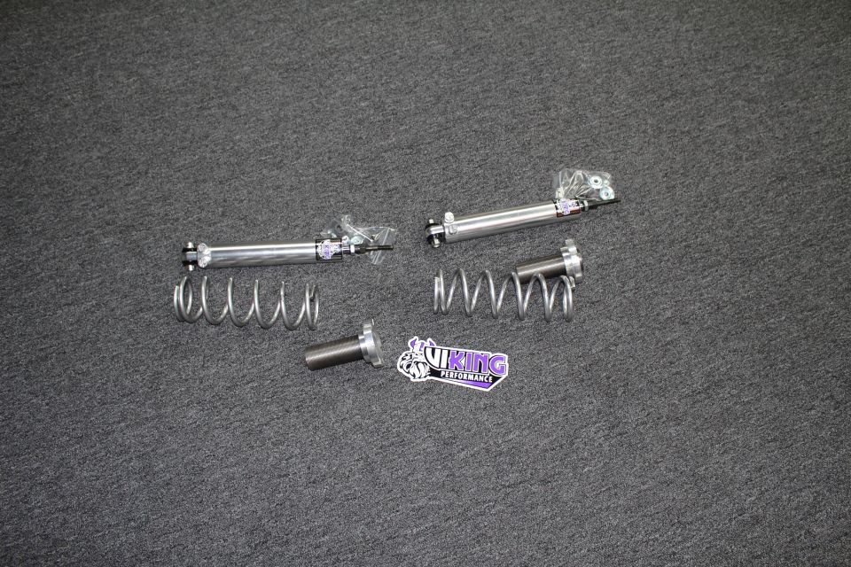 Two Viking shock bodies, coil springs, and a threaded billet sleeve with Viking Performance decal on carpet