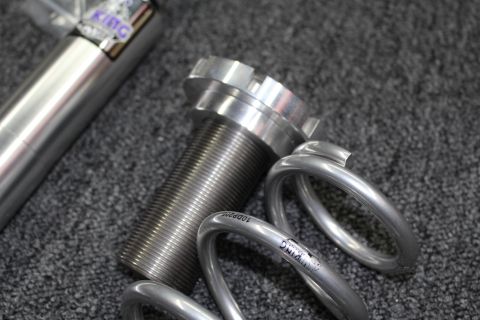 2003 Ford Crown Victoria - threaded coilover shock body with adjustable spring perch beside coiled silver suspension springs marked 10DP200.