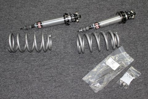 2003 Ford Crown Victoria - Two polished adjustable coilover shocks laid out beside gray coil springs and bagged mounting hardware on gray carpet.