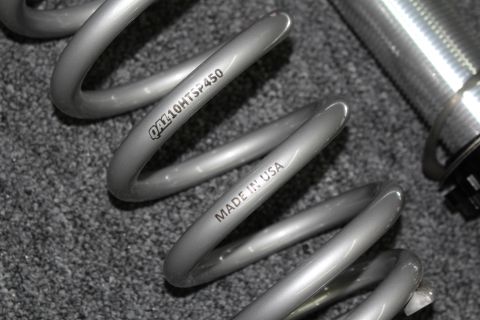 2003 Ford Crown Victoria - Detail of a gray suspension coil spring stamped QA110HTSF450 and MADE IN USA next to a threaded shock body.