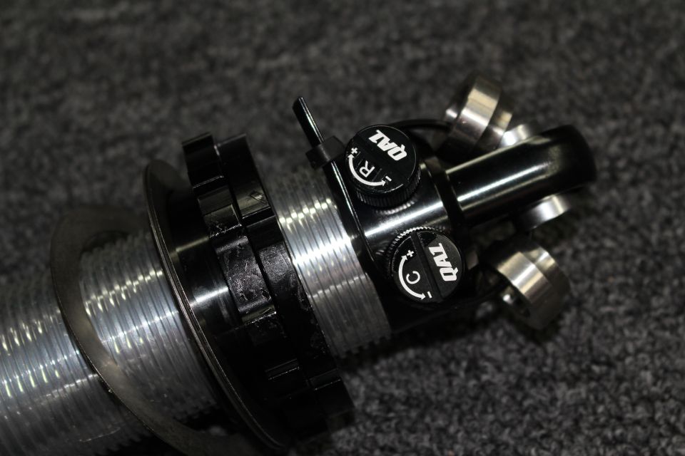 Black-anodized coilover top mount with two QA1 R and C adjustment knobs