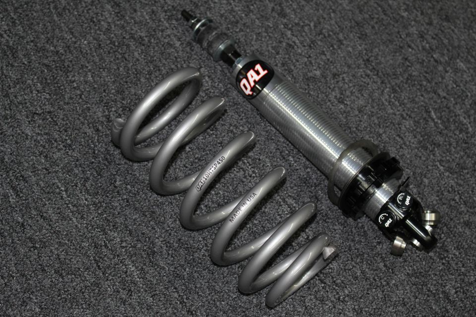 Single QA1 coilover shock with gray coil spring marked QA110HTSF450 on dark carpet