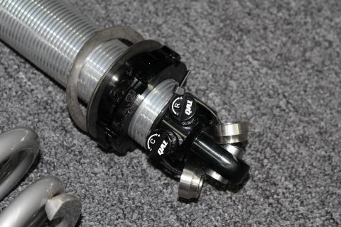 2003 Ford Crown Victoria - Close-up of a QA1 coilover's threaded upper body, spanner-nut perch, and rebound and compression adjuster knobs.