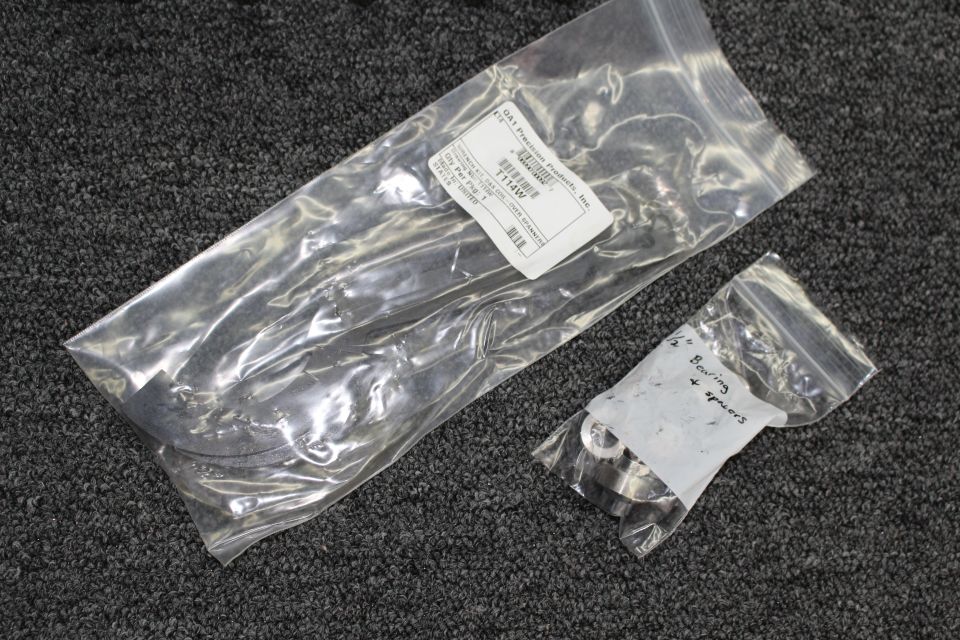 Two clear plastic bags of metal suspension hardware with labels on carpet