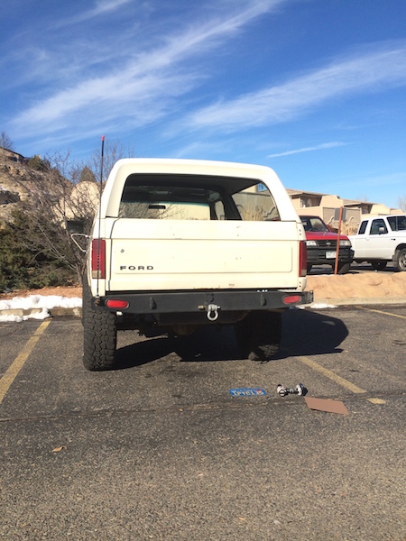 1981 Ford Bronco - The rear of a white Ford Bronco is shown in a parking lot with other vehicles in the background.