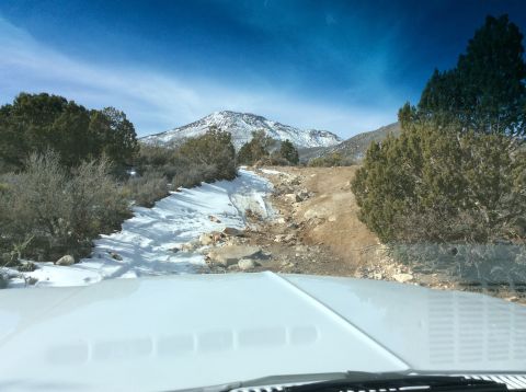 1979 Ford Bronco - The vehicle is on a rough, snow-covered path leading up a mountain in a dry, arid landscape.