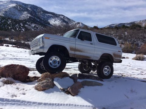 1979 Ford Bronco - A lifted 1978 Ford Bronco navigates rocky terrain in a snowy, mountainous area.