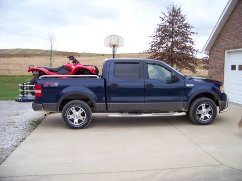 1984 Honda ATC 250 R - A blue pickup truck is parked on a concrete driveway with a red ATV loaded in its bed.