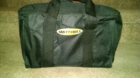 1979 Ford Bronco - A black Smittybilt bag sits on carpeted stairs. The bag has two handles and a zippered top.