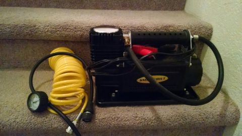1979 Ford Bronco - Portable air compressor with tire gauge and hose sits on carpeted stairs.