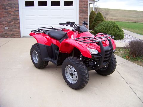 1984 Honda ATC 250 R - A red ATV is parked on a concrete driveway in front of a brick house and garage.