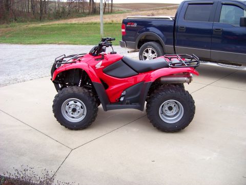 1984 Honda ATC 250 R - A red all-terrain vehicle is parked on a concrete driveway next to a blue pickup truck.