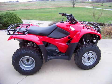 1984 Honda ATC 250 R - A red ATV with a Honda logo is parked on a concrete surface with a grassy field in the background.