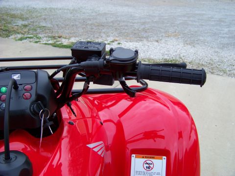 1984 Honda ATC 250 R - Handlebar and control cluster of a red ATV, showing the throttle, brake lever, and ignition.