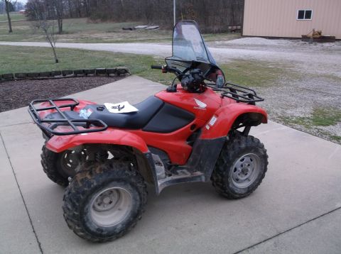 1984 Honda ATC 250 R - A red Honda ATV is parked on a concrete surface outdoors, with a clear windshield and storage racks.