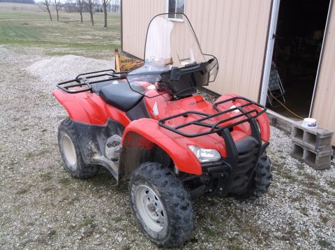 1984 Honda ATC 250 R - This red ATV features a clear windshield and black cargo racks, parked on a gravel surface.