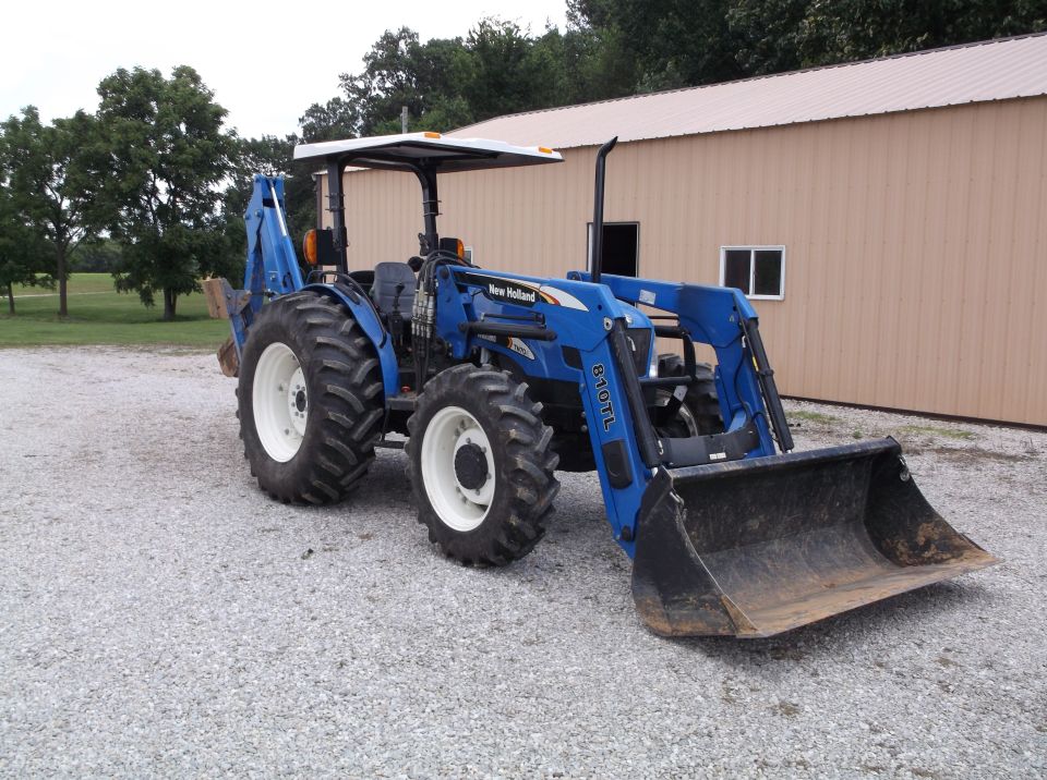 Blue New Holland tractor with front loader and backhoe attachment