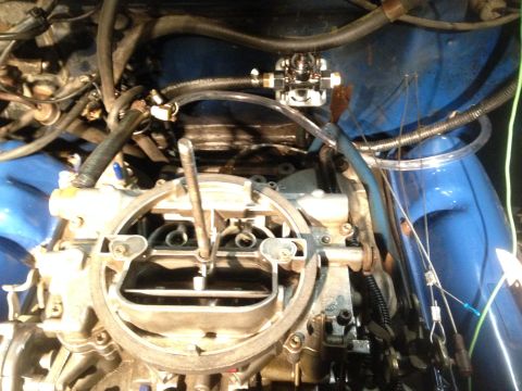 1979 Ford Bronco - Close-up view of an engine bay, focusing on the carburetor and an aftermarket fuel pump assembly.