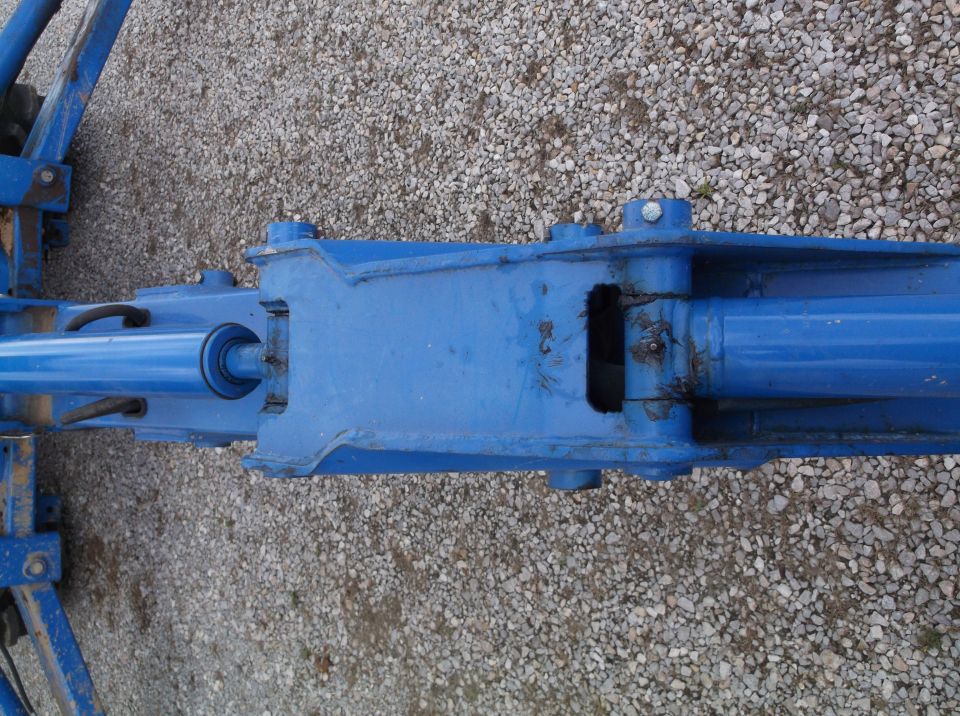 Close-up of a blue hydraulic cylinder assembly with metal pins and linkages