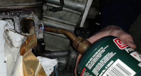 1996 Ford Bronco - A mechanic uses a torch to heat a bolt on an engine block during a repair.