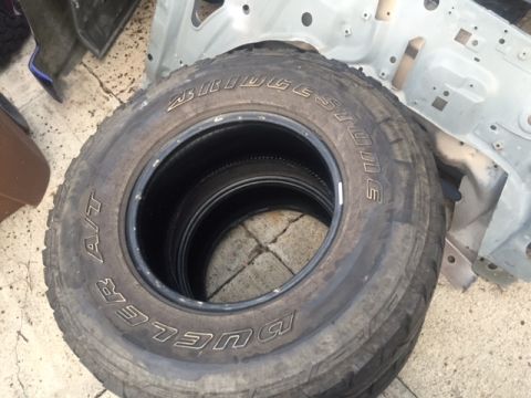 1986 Ford Bronco - A set of Bridgestone Dueler A/T tires are visible, with the brand name clearly displayed on the sidewall.