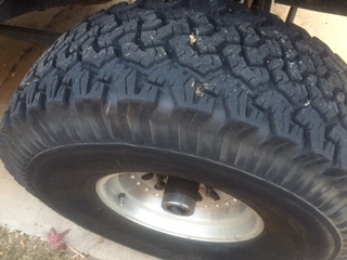 1986 Ford Bronco - A close-up shot focuses on the tread of a large off-road tire mounted on a silver alloy wheel.