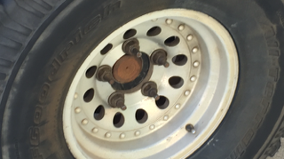 1986 Ford Bronco - Close-up of a BFGoodrich All-Terrain KO tire mounted on a white aftermarket wheel, showing the tire tread and wheel lug nuts.