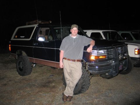 1995 Ford Bronco - A man poses with a lifted Ford Bronco, with other vehicles visible in the background at night.