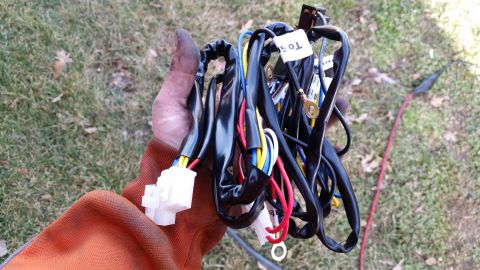 1981 Ford Bronco - A hand holds a complex wiring harness with multiple colored wires and white connectors, a label with text.