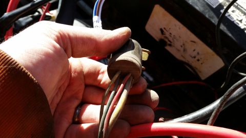 1981 Ford Bronco - A hand is shown holding an electrical connector with several wires attached, likely part of a vehicle's wiring system.
