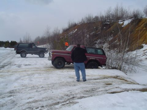 1993 Ford Bronco - Two Ford Broncos navigate a snowy, off-road terrain with a person observing the maroon vehicle.