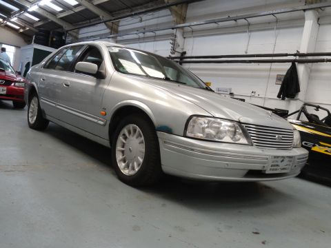1999 Ford Fairlane - A silver sedan is parked in a garage, with another vehicle partially visible on the left.