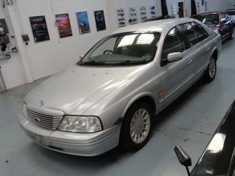 1999 Ford Fairlane - A silver sedan is parked indoors, with other vehicles visible in the background. The registry lists it as a 1999 Ford Fairlane.