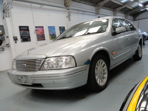1999 Ford Fairlane - Silver 1999 Ford Fairlane sedan is parked inside a garage with posters on the wall.