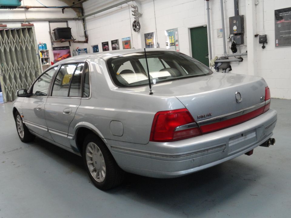 Silver sedan parked inside a garage. Rear view shows taillights and bumper