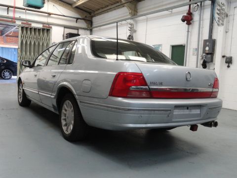 1999 Ford Fairlane - A silver sedan is parked in a garage, showing its rear end and a watermark for SUPERMOTORS.NET.