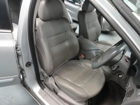 1999 Ford Fairlane - Interior view of a car with gray leather seats and dashboard, showing the steering wheel and center console.