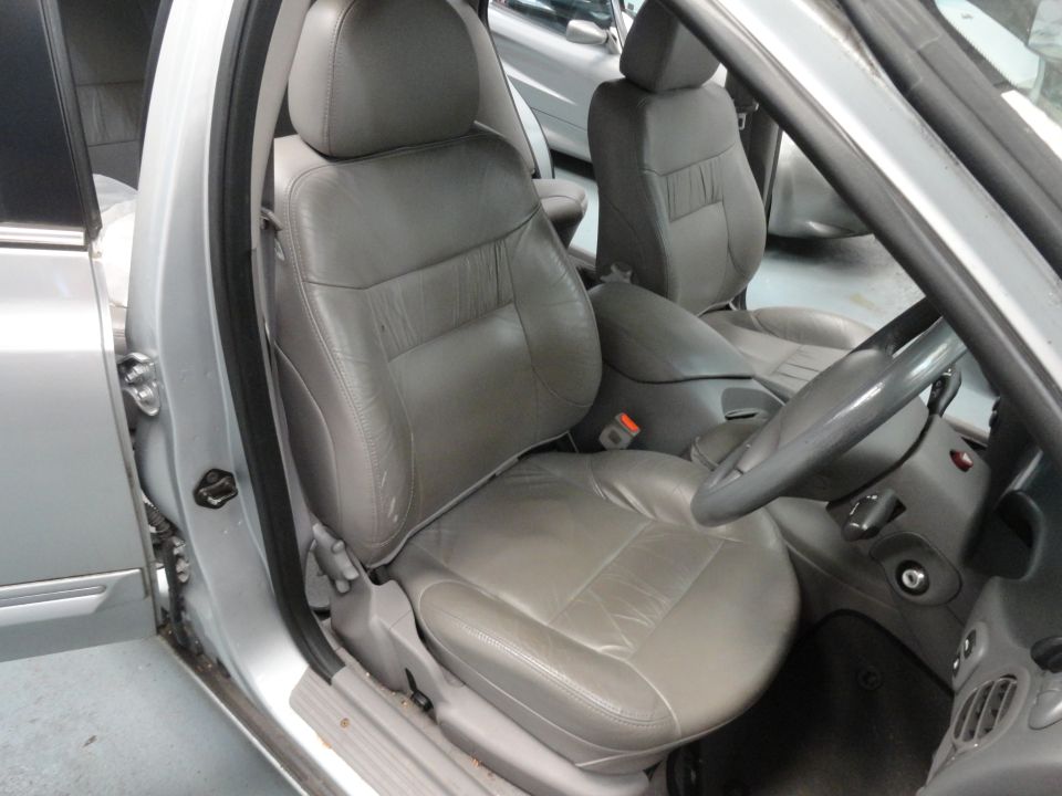 Silver car interior with gray leather seats, dashboard, and steering wheel. Another car is visible in the background