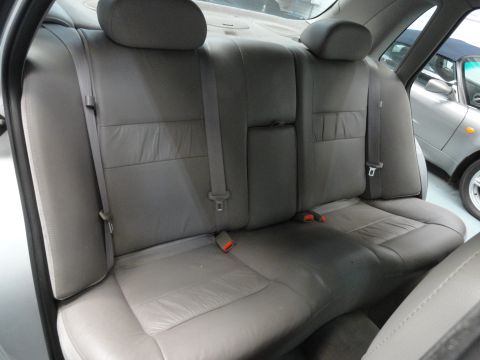 1999 Ford Fairlane - Interior view of gray leather rear seats and seatbelts, with another vehicle visible outside.