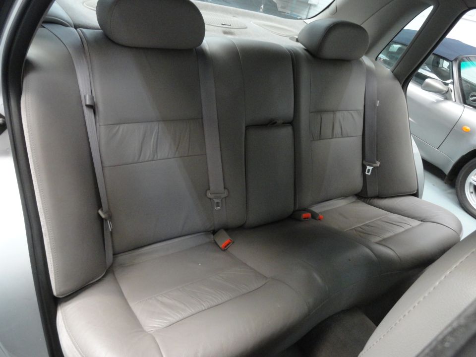 Gray leather rear seats with seatbelts. Another car is visible through the window